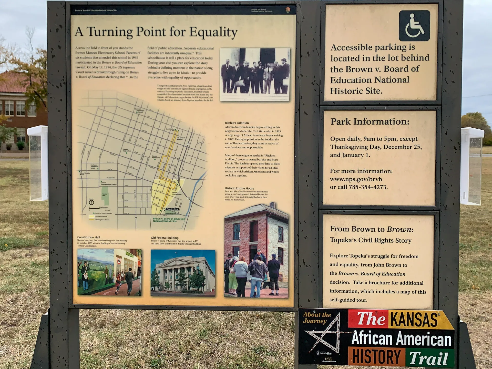 Informational display at the Brown v. Board of Education National Historic Site. Includes text about equality, a historic map, images of related events, and park information. Sign mentions parking access and has logos for the Kansas African American History Trail.