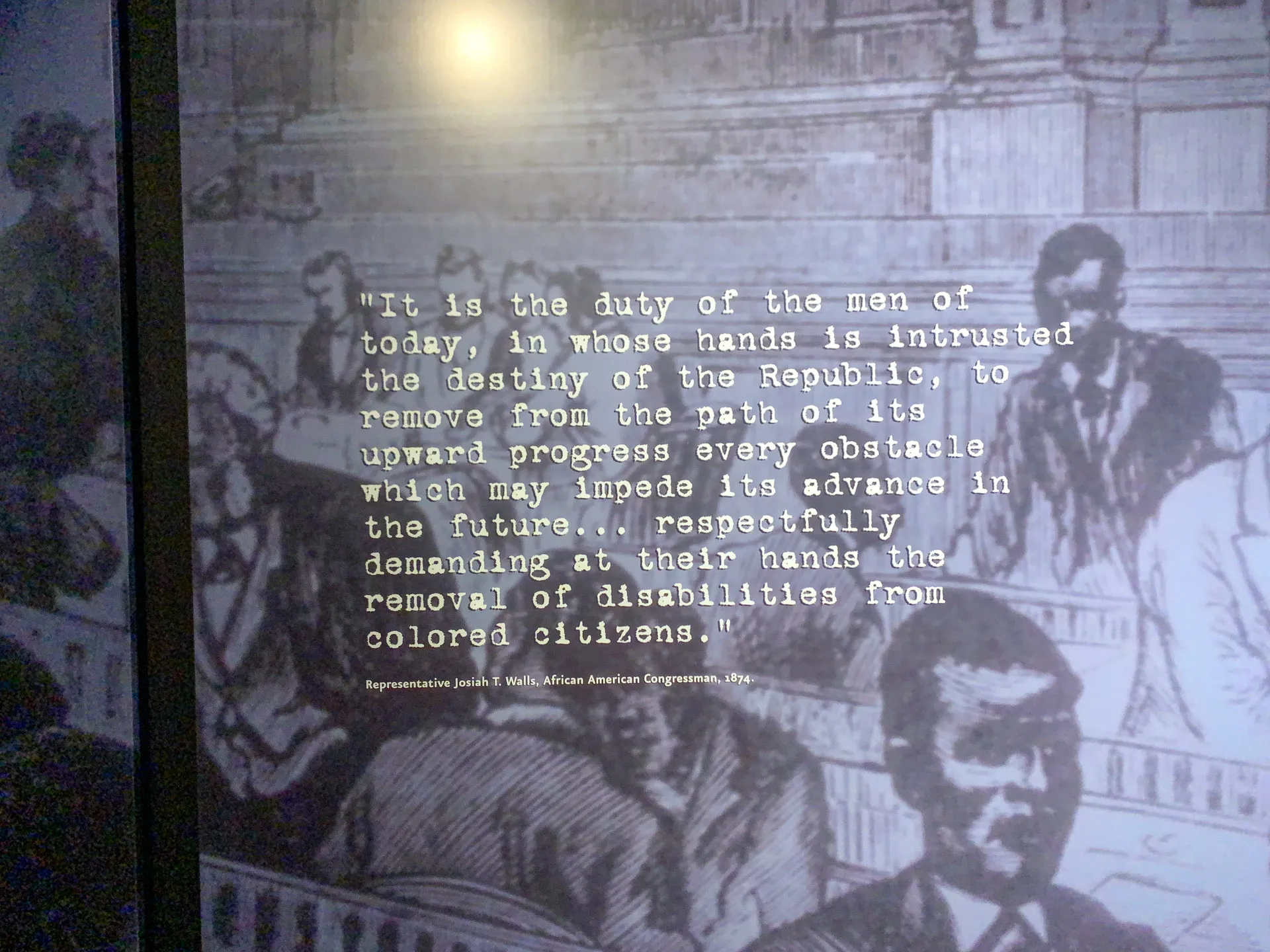 A black and white historical image depicts a group of men seated in a formal setting, likely a government chamber. Overlaid is a quote about duty and removing obstacles for colored citizens, attributed to Representative Josiah Walls, an African American Congressman from 1876.