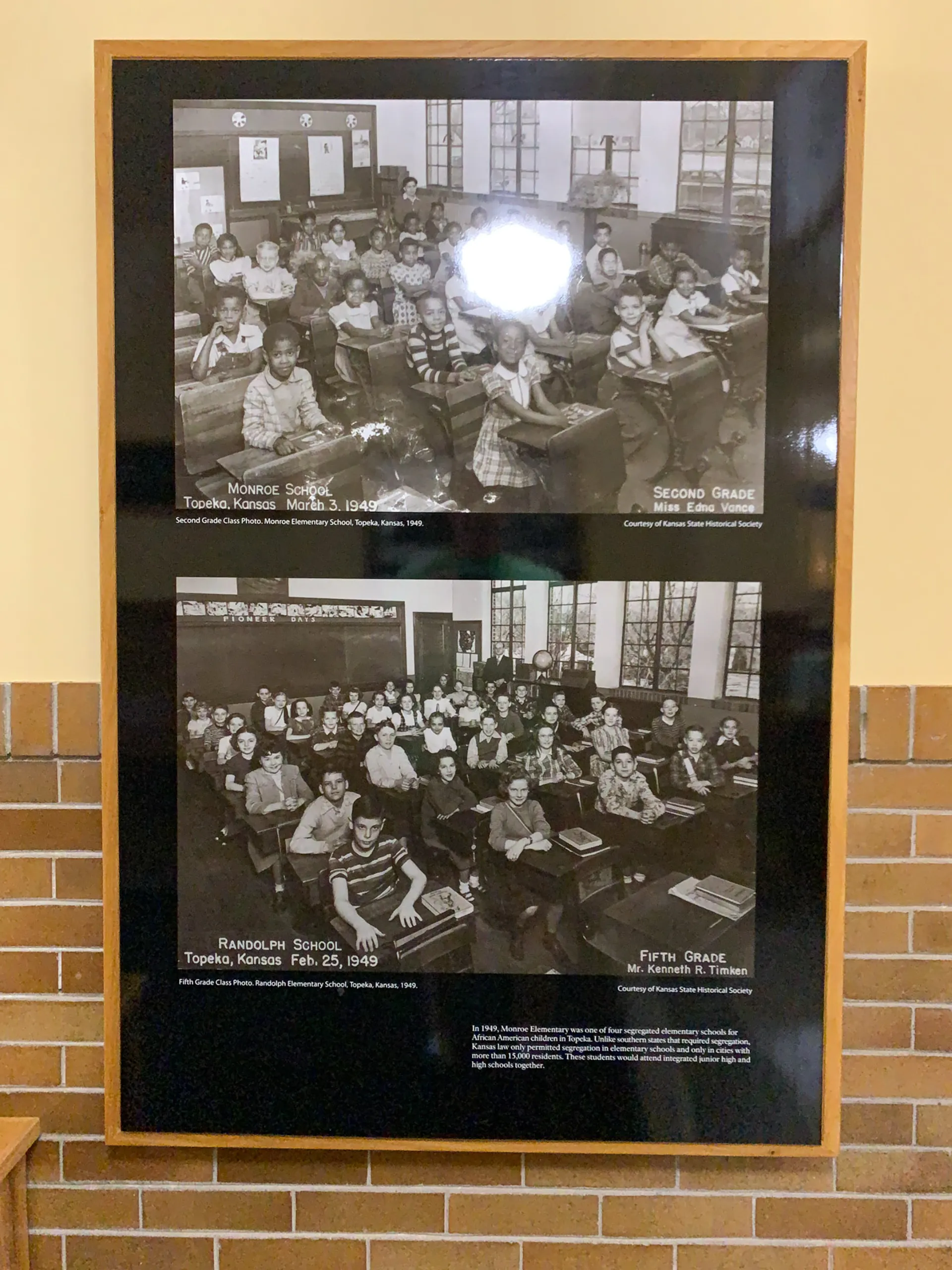 Two black-and-white photos in a frame. The top photo shows a classroom with young children at Monroe School, Topeka, Kansas, in 1949. The bottom photo features a fifth-grade class at Randolph School, also in Topeka, dated February 23, 1949. Both images depict orderly classrooms.