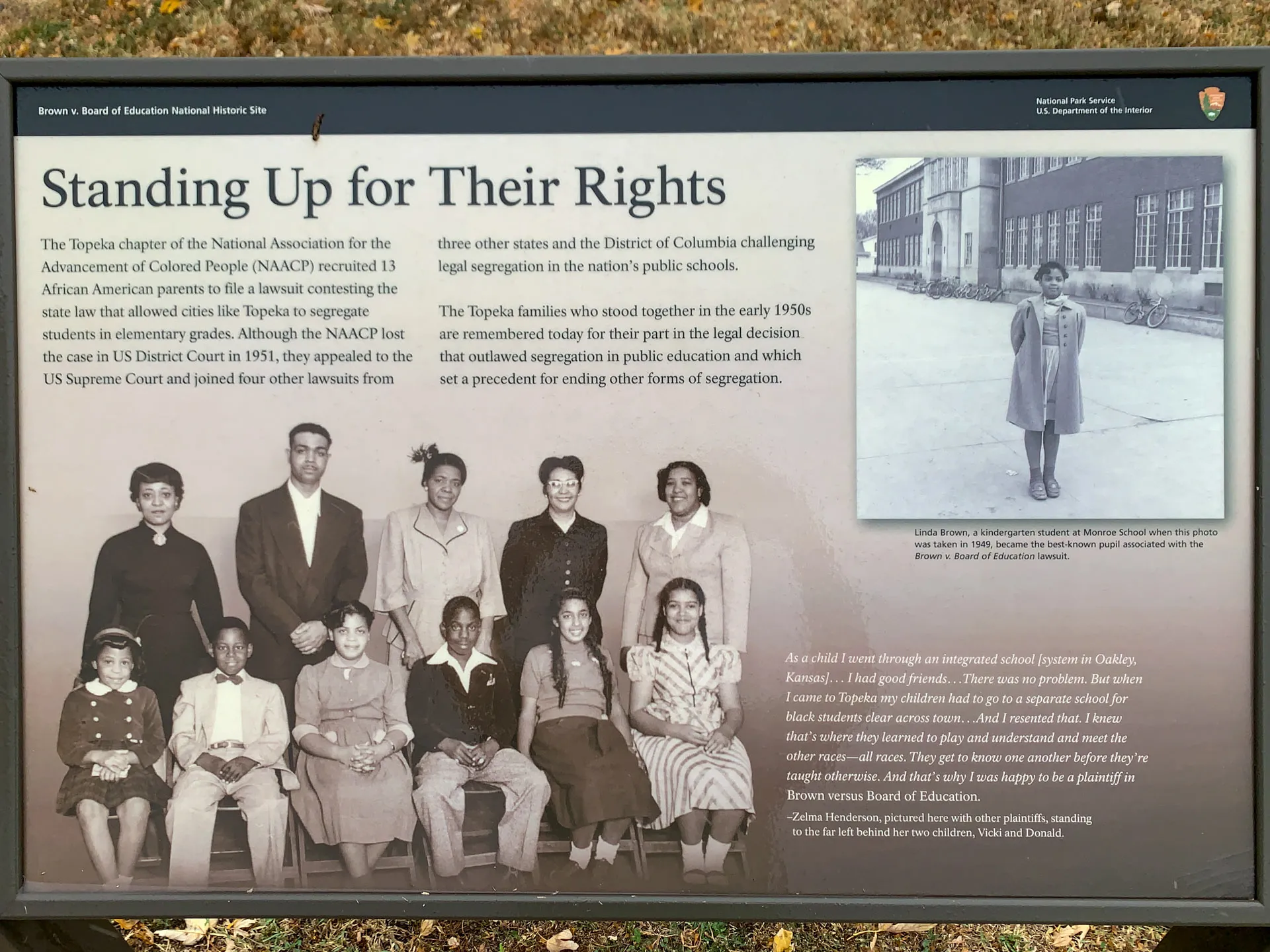 A historical information sign titled "Standing Up for Their Rights." It features a black-and-white photo of students and families involved in desegregation lawsuits, accompanied by text about their legal battles. The sign includes another photo of Linda Brown on a sidewalk.