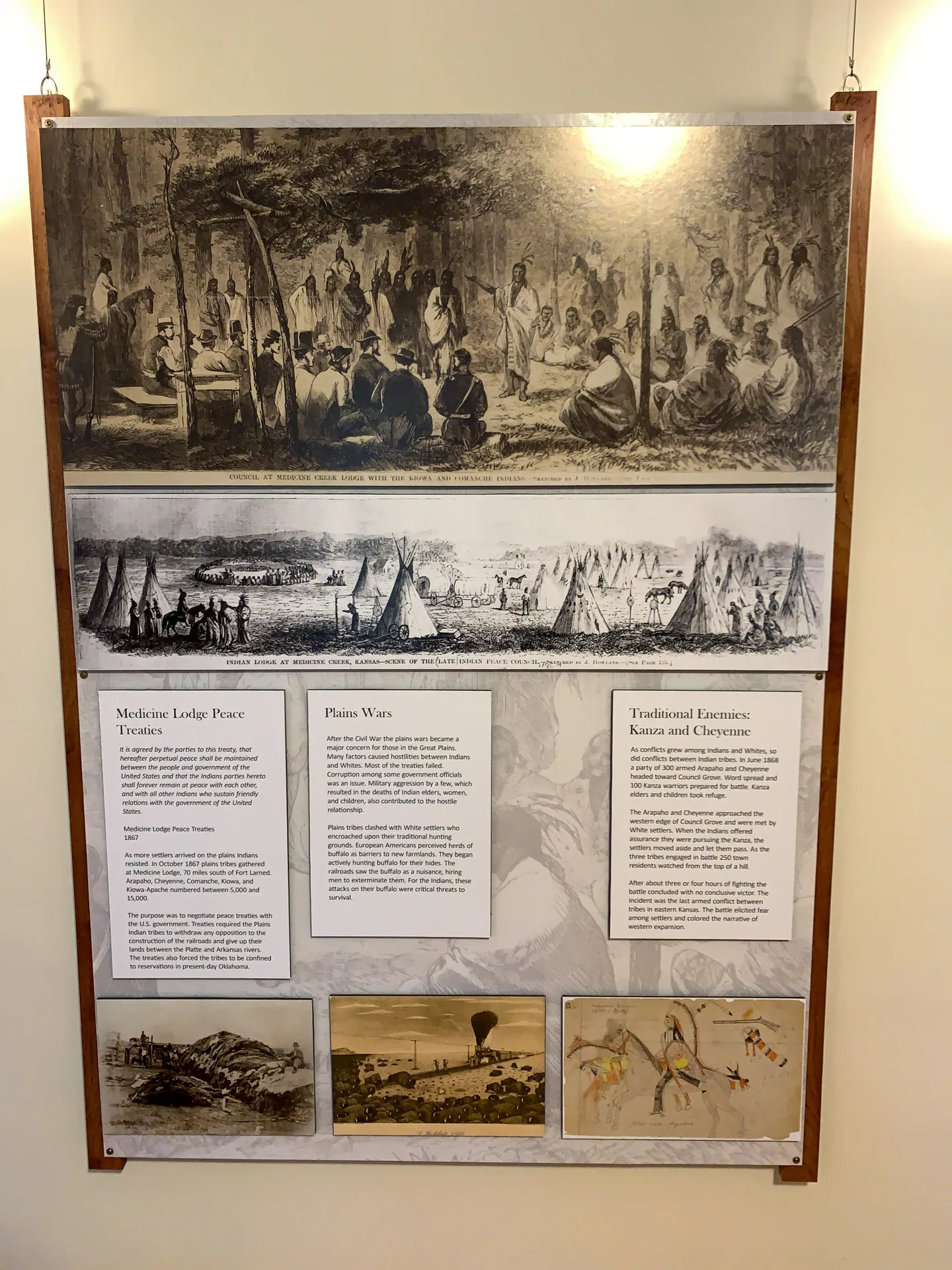 A display board featuring historical illustrations and text. The top section shows a group of people in a forest setting. Below are scenes with tents and figures, related to Medicine Lodge Peace, Plains Wars, and Tribal Traditions. Three more illustrations depict landscapes and activities.