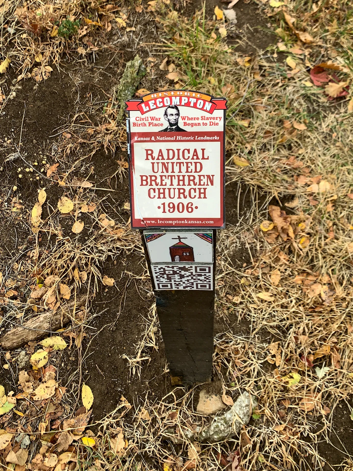 Signpost for the Radical United Brethren Church, 1906, in Lecompton, Kansas, mentioning its historical significance related to the Civil War and slavery.