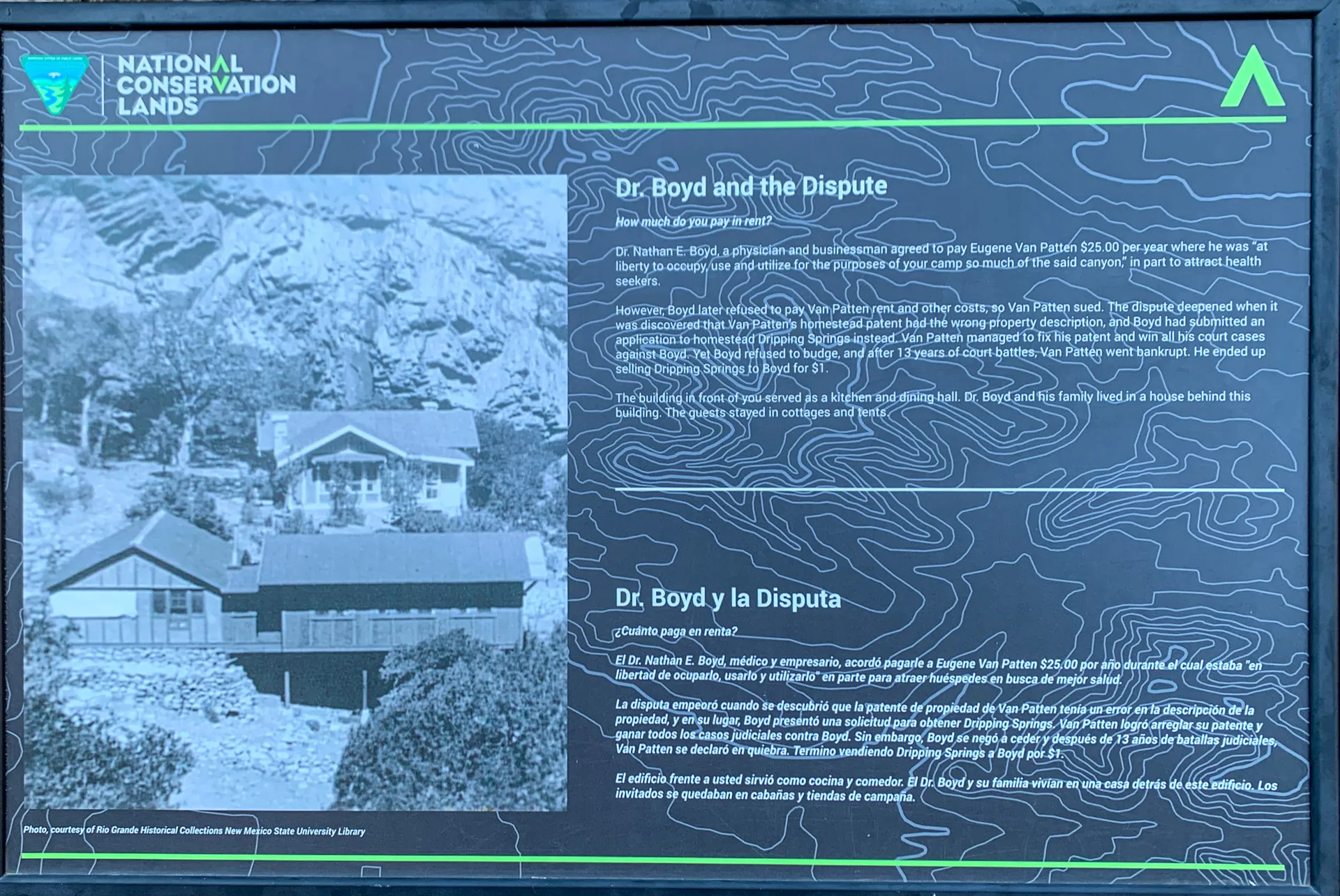 A bilingual informational sign titled "Dr. Boyd and the Dispute" against a dark, topographic map background. It features a grayscale image of a house surrounded by trees. Text provides a historical account regarding land and legal issues. National Conservation Lands logo is at the top.