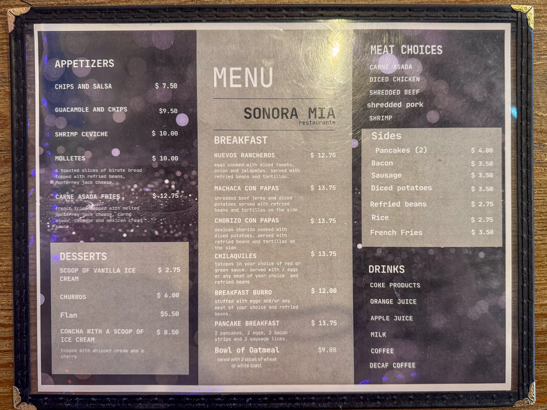 A menu from Sonora Mia Restaurant is displayed, featuring appetizers like chips and salsa, a variety of breakfast items, meat choices such as carne asada and shredded pork, sides including pancakes and bacon, desserts like ice cream and churros, and drinks such as coffee and milk.