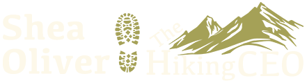 Light yellow graphic Header designed for Elementor or WordPress sites, featuring “Shea Oliver” on the left, a hiking boot print in the center, and “Hiking CEO” on the right. Stylized mountain peaks in olive green appear above “CEO.” The background is pale gray.