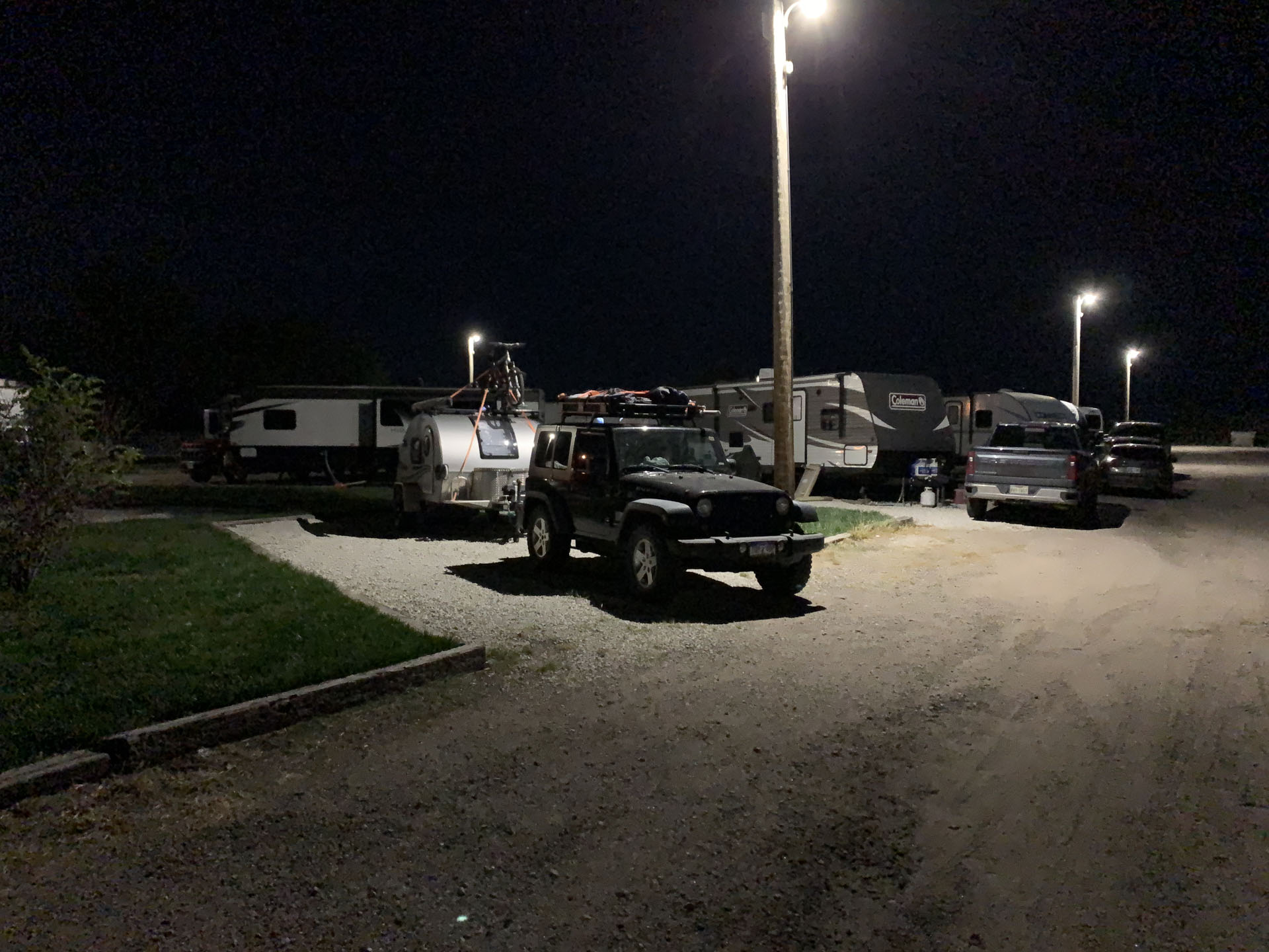 Two Cimmeron RVs parked in a gravel lot at night.